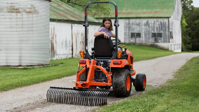 Land Pride LR05 Series Landscape Rake attached to the back of a Kubota tractor on a dirt path.