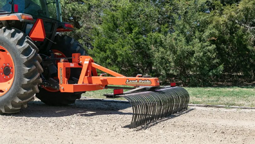 Land Pride LR37 Series Landscape Rake attached to the back of a Kubota tractor working a field.