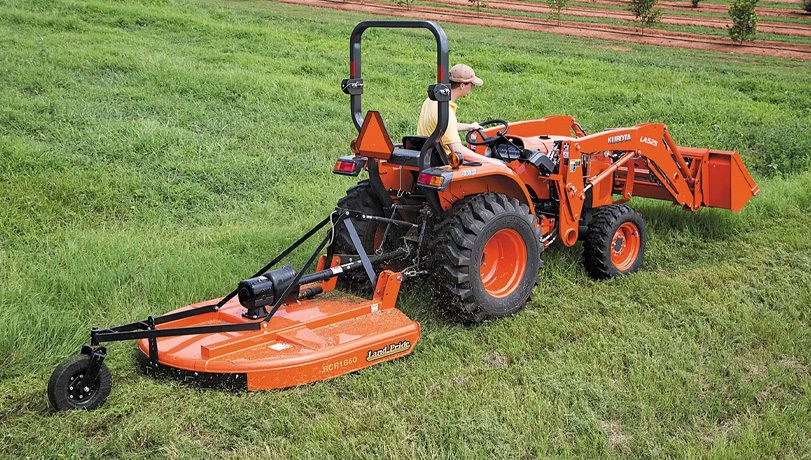 Person driving a Kubota tractor with a Land Pride RCR18 Series Rotary Cutter attachment.