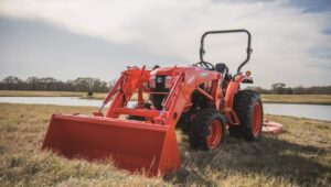 Kubota tractor with excavator attachment in front of a creek.