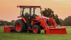 Kubota L4060HSTC-LE Tractor in a field with an excavator attachment in a field at sunset.