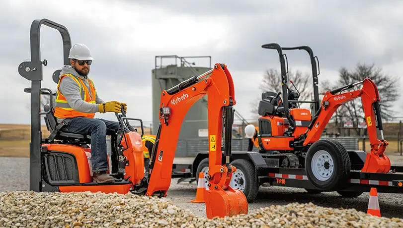 Person operating a Kubota K008 Excavator digging up gravel.